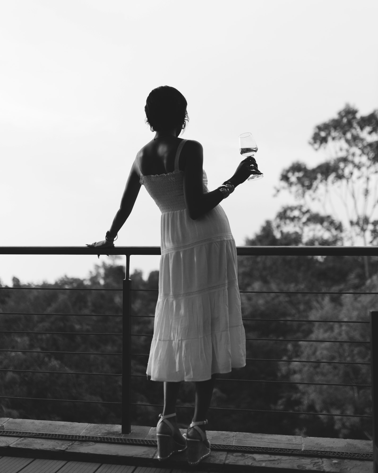Silhouette of a woman in a white dress on a balcony at dusk