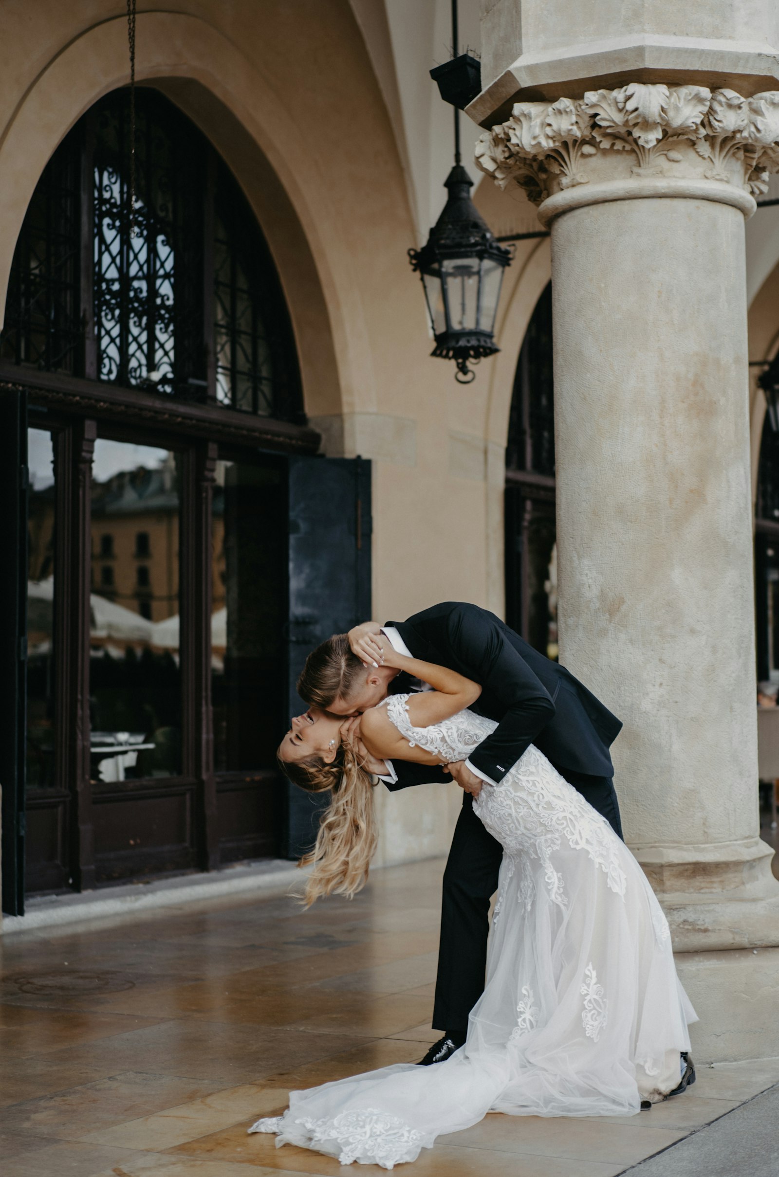 A bride and groom embrace beneath an archway