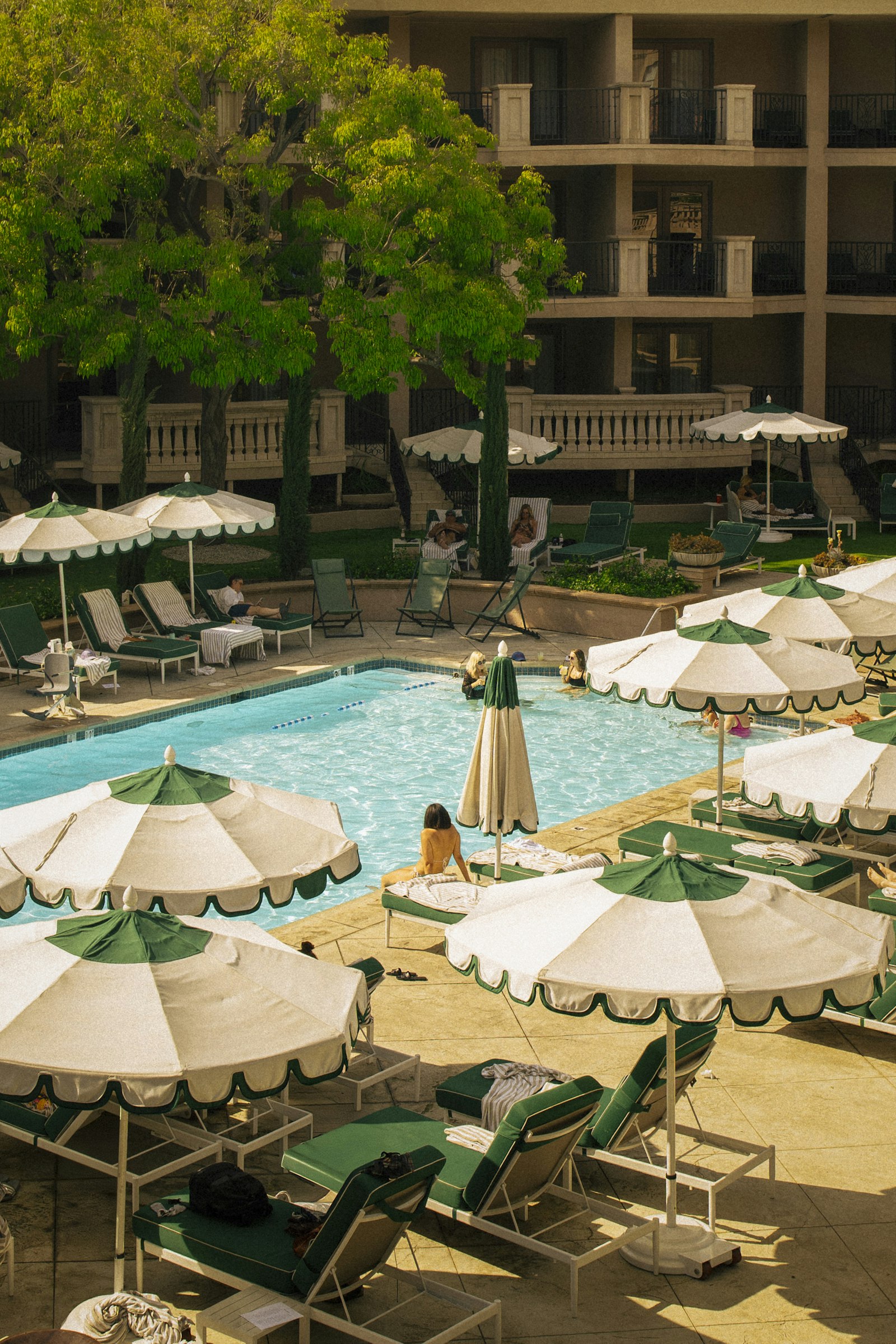 A poolside scene with striped umbrellas and lounge chairs