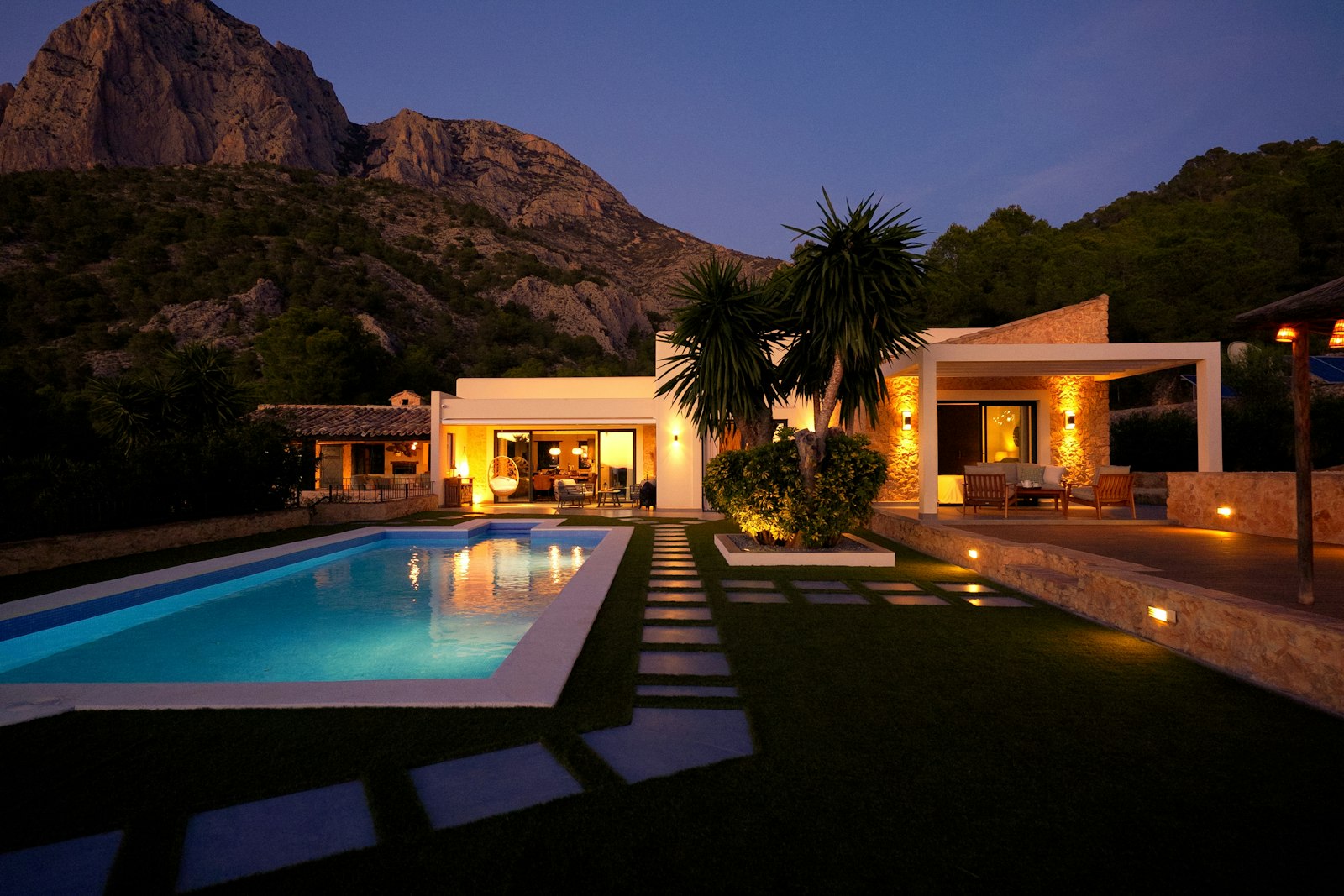 A modern villa with pool at dusk, mountains beyond