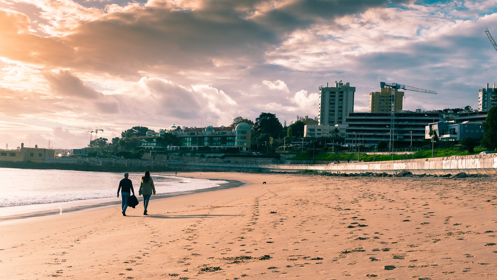A couple walking along a beach at golden hour