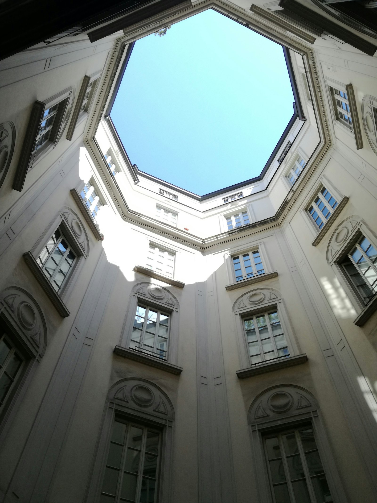 Looking up at an ornate courtyard building against a blue sky